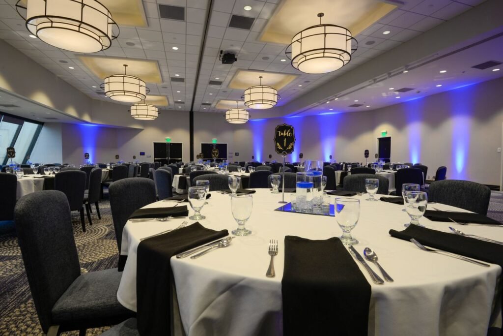 pexels-photo-14636319-14636319 Spacious banquet hall with round tables set for an event featuring elegant lighting and decor.